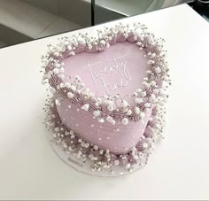 a pink heart shaped cake on top of a table