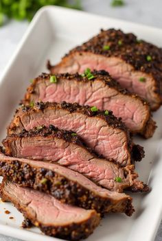 slices of sliced meat on a white plate with garnishes and seasoning