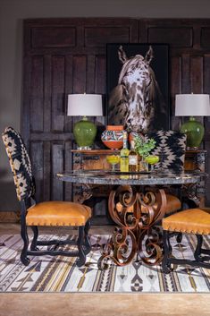 a dining room table with four chairs and a horse painting on the wall behind it