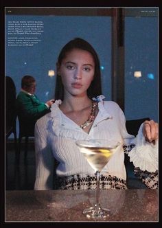 a woman sitting at a table with a martini in front of her