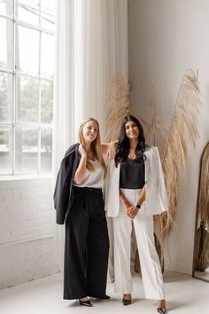 two women standing next to each other in front of a window