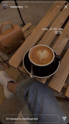 a cup of coffee sitting on top of a wooden table next to a handbag