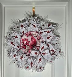 a paper wreath hanging on a door with red and white decorations in the shape of hearts