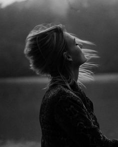 black and white photograph of a woman with her hair blowing in the wind looking up