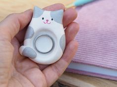 a person holding a ring in their hand with a cat figurine on it