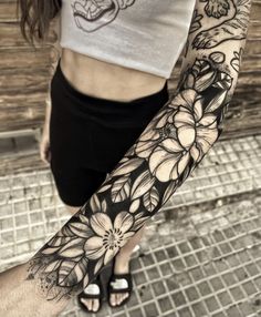 a woman's arm with black and white flowers on the left side of her body