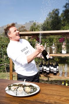 a man is pouring wine into his plate with oysters on the table next to him