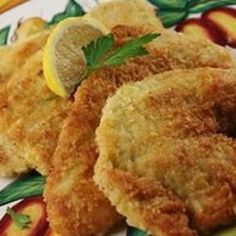 some fried food on a plate with lemon wedges