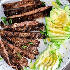 steak, avocado and sesame seeds on a white plate with green garnish