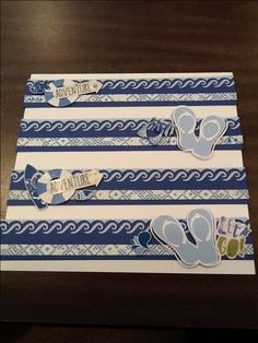 two pieces of paper with blue and white designs on them sitting on top of a wooden table