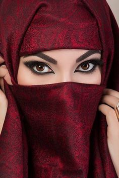 a woman wearing a red hijab covering her face and looking at the camera