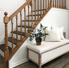 a white couch sitting under a stair case next to a wooden bannister on top of a hard wood floor