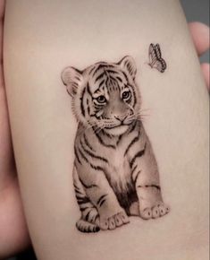 a small tiger cub tattoo on the arm