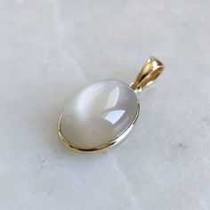 ITEM DESCRIPTION: >>The pendant is made from Solid 14K Yellow Gold. Gemstone used is absolutely natural and ethically sourced. >>Natural White Moonstones cabochon shape with bezel setting are studded on it with utmost precision. >>This is a minimalist design and is absolutely hassle-free and everyday jewelry. ✓ Gem: White Moonstone ✓ Gem size: 10x14 mm ✓ Gem weight: 7.09 carats ✓ Gold purity: 14K (58.33% approx.) ✓ Gold weight: 0.56 grams ✓ Gross weight: 1.98 grams The Gold purity is guaranteed Oval Cabochon Pendant, White Oval Cabochon Birthstone Jewelry, White Moonstone Jewelry Oval Cabochon, White Oval Cabochon Jewelry With Large Stone, White Oval Cabochon Gemstones, White Oval Jewelry With Bezel Setting, White Oval Gemstones For Gifts, Jadeite Jewelry, Handmade Jewelry Box