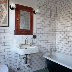 a bath room with a toilet a sink and a bath tub next to a mirror