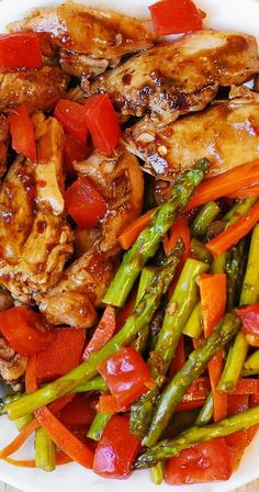 a white plate topped with chicken, asparagus and tomatoes