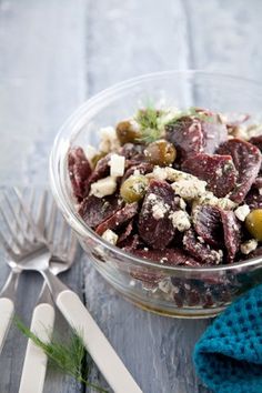 a glass bowl filled with food next to silverware