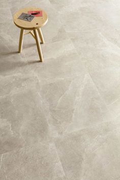 a small wooden table sitting on top of a white tile floor next to a chair