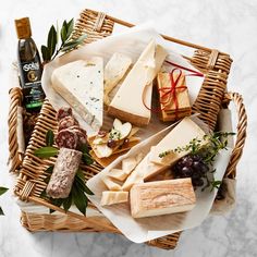 an assortment of cheeses and crackers in a wicker basket on a marble table