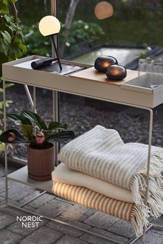 a table with some towels on it and a lamp next to it in front of a window