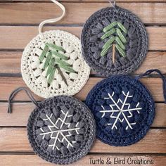 three crocheted snowflakes are sitting on a wooden surface