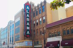 an old theater sign on the side of a building in front of other tall buildings