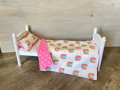 a small child's bed with pink polka dots and rainbows on it