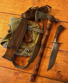 an assortment of knives and sheaths laid out on a wooden floor next to a bag