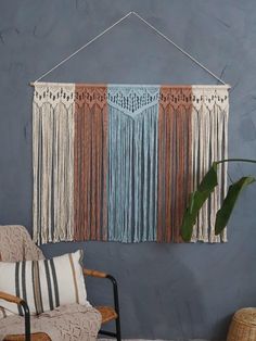 a wall hanging on the side of a blue wall next to a wicker chair