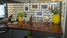 a desk with a computer, phone and other office supplies on it in front of a chevron wall