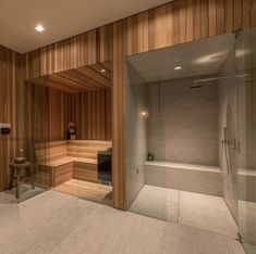 a bathroom with wooden walls and a glass shower door that leads to a sauna