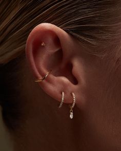 a woman's ear with two small diamond hoops