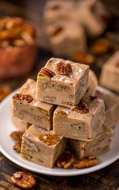 several pieces of pecan nut fudge on a white plate with nuts around it