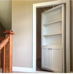 an open door leading to a room with white walls and wooden stairs in the corner