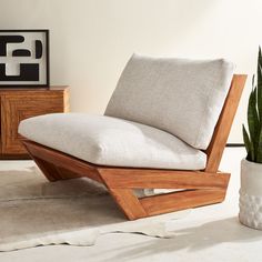 a wooden chair sitting on top of a floor next to a potted plant in a living room