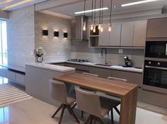 a modern kitchen with an island table and stainless steel appliances on the wall behind it