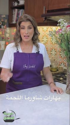 a woman standing in front of a counter with flowers on it and the words, chef maid written in arabic