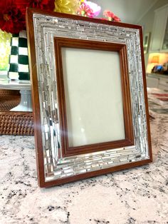 a wooden frame sitting on top of a counter next to a vase filled with flowers