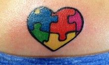 a heart shaped puzzle piece tattoo on the back of a woman's stomach,