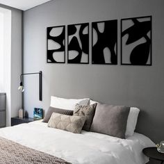 a bedroom with three black and white paintings on the wall next to a bed in front of a window