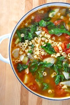 a bowl filled with soup and vegetables on top of a wooden table