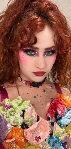 a woman with red hair and makeup is dressed up as a flowered dress, posing for the camera