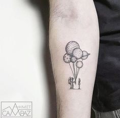 a man with a tattoo on his arm holding onto some balloons that are floating in the air