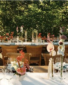 an outdoor dining area with tables, chairs and flowers in vases on the table