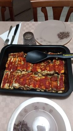 a pan with food on it sitting on a table next to plates and utensils