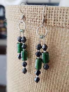 Cylindrical green glass beads, faceted black glass beads, and seed beads are used to decorate these earrings. All the different shapes and offset lines create a pleasing pattern of variety. Black Czech Glass Jewelry With Ear Wire, Green Jewelry With Black Round Beads, Green And Black Beaded Earrings For Gifts, Green Beaded Earrings With Black Beads For Gift, Green Glass Beaded Dangle Earrings, Kalispell Mt, Bead Dangle Earrings, Beaded Dangle Earrings, Etsy Earrings Dangle