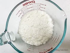 a glass bowl filled with white flour next to a measuring cup on top of a counter