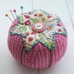 a pink and white pin cushion sitting on top of a tile floor next to a wall