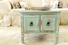 a blue table with two drawers in front of a couch