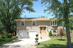 a house with two garages and trees in the front yard